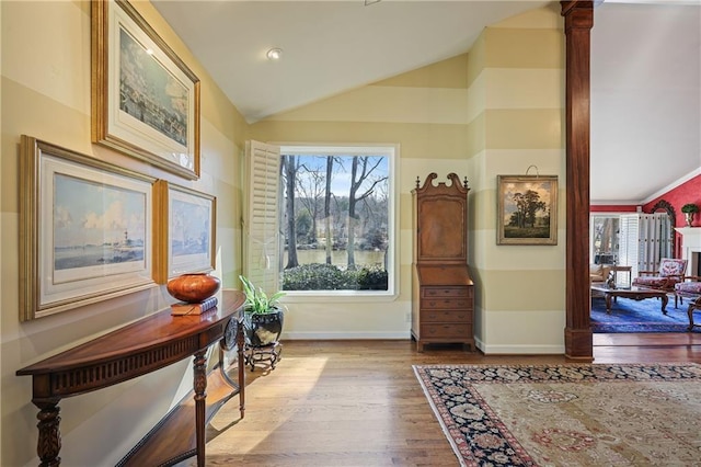 entryway featuring lofted ceiling, light wood-style flooring, and baseboards