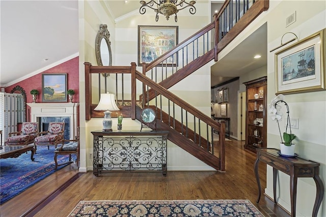 stairs featuring a fireplace, crown molding, visible vents, and wood finished floors