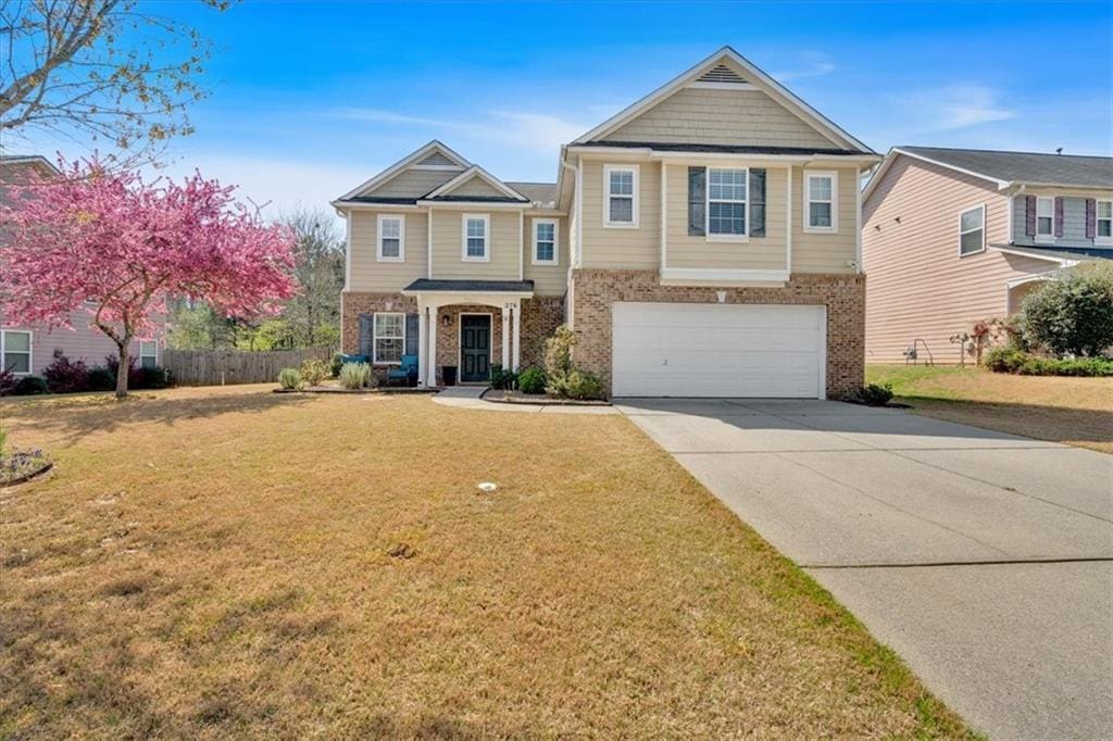 view of front of home with driveway, a front yard, an attached garage, and brick siding