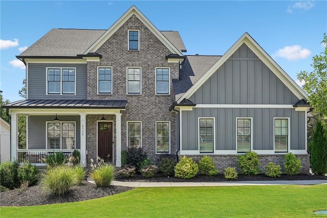 view of front of home with a standing seam roof, brick siding, board and batten siding, and a front yard