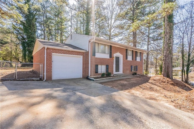 raised ranch featuring concrete driveway, brick siding, fence, and an attached garage