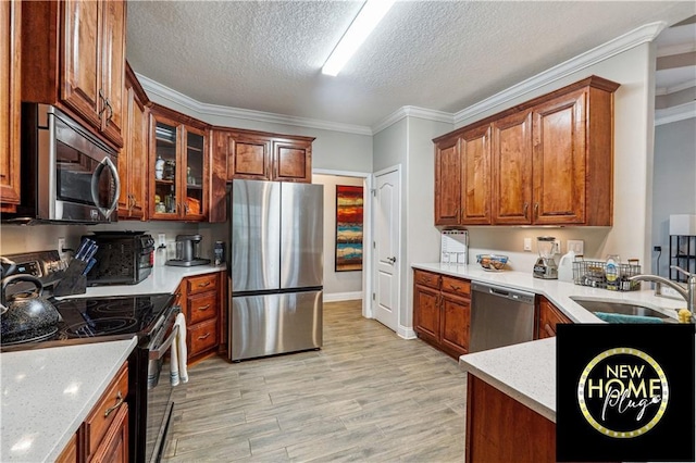 kitchen featuring light wood-style flooring, stainless steel appliances, a textured ceiling, crown molding, and a sink