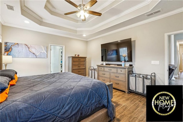 bedroom with a tray ceiling, light wood-type flooring, visible vents, and crown molding