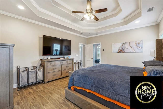 bedroom with ceiling fan, visible vents, light wood-style floors, a tray ceiling, and crown molding