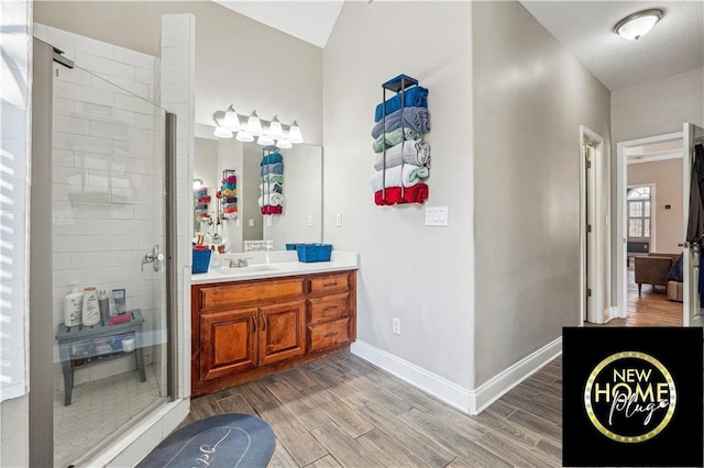 bathroom featuring a shower stall, vanity, baseboards, and wood finish floors