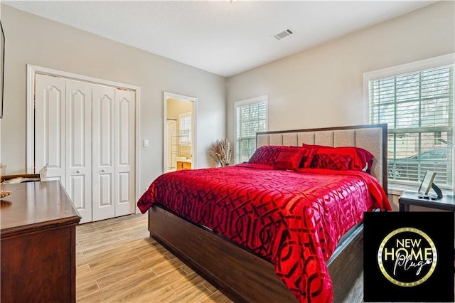 bedroom with light wood-type flooring, a closet, visible vents, and ensuite bath