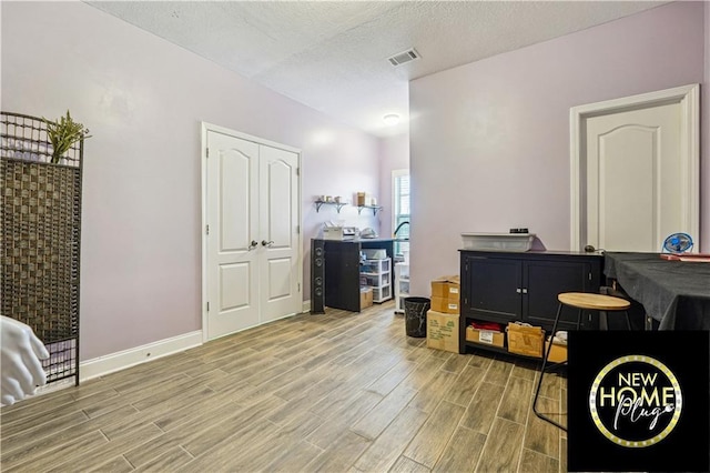 playroom with wood tiled floor, visible vents, a textured ceiling, and baseboards