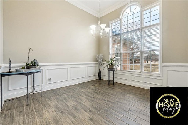 dining area featuring crown molding, a decorative wall, wainscoting, wood finished floors, and a chandelier