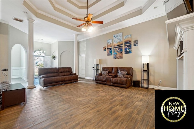 living area featuring ceiling fan with notable chandelier, visible vents, dark wood-style floors, a tray ceiling, and ornate columns