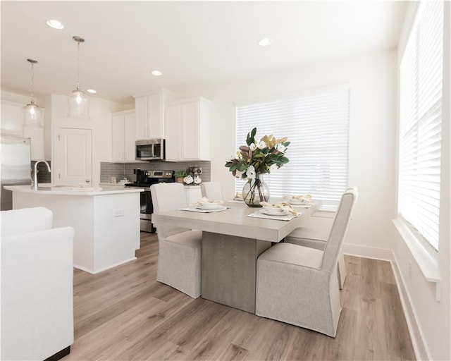 dining space with sink and light hardwood / wood-style floors