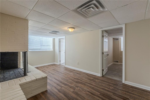 unfurnished living room featuring a fireplace, dark hardwood / wood-style floors, and a paneled ceiling