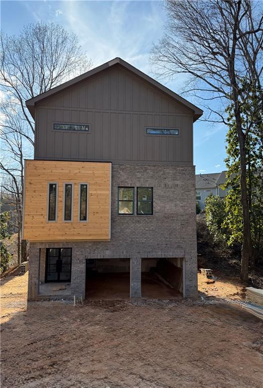 exterior space featuring a garage, driveway, brick siding, and board and batten siding