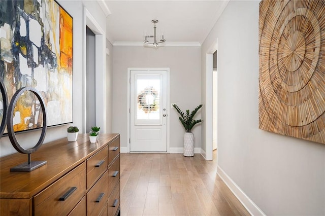 doorway with a notable chandelier, light hardwood / wood-style flooring, and ornamental molding