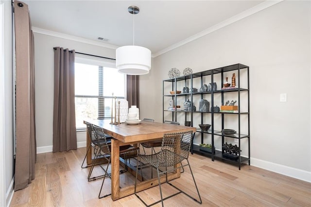 dining space featuring crown molding and light hardwood / wood-style flooring