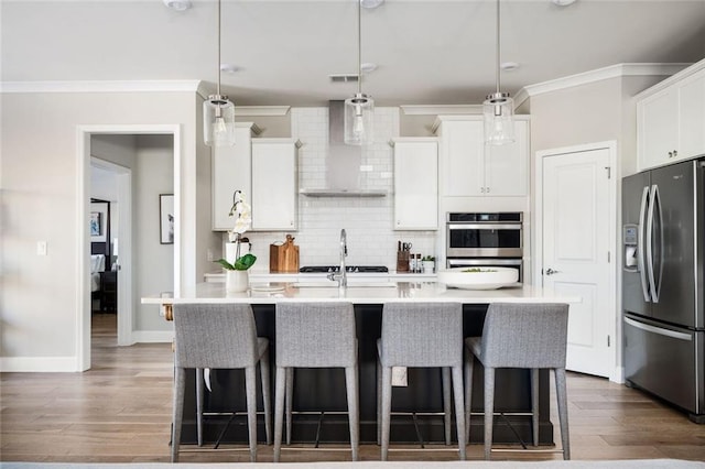 kitchen featuring white cabinetry, decorative light fixtures, stainless steel fridge with ice dispenser, and a center island with sink