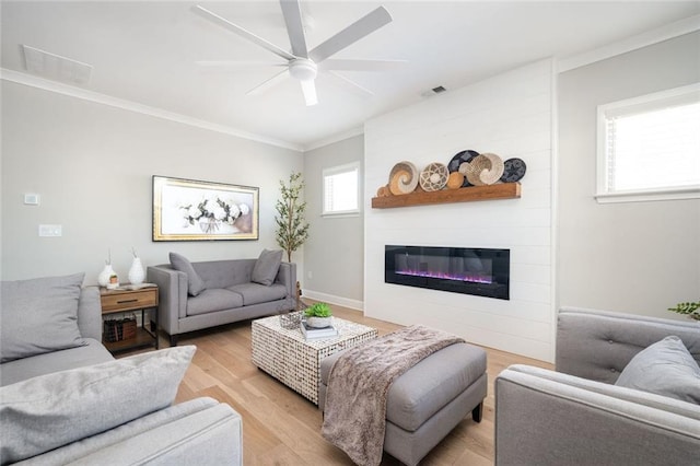 living room featuring crown molding, ceiling fan, a fireplace, and light hardwood / wood-style flooring