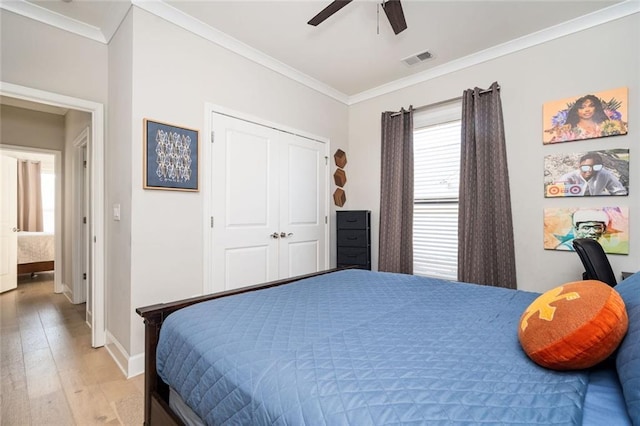 bedroom featuring ornamental molding, light hardwood / wood-style floors, ceiling fan, and a closet