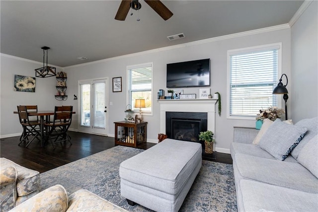 living area featuring baseboards, visible vents, a glass covered fireplace, wood finished floors, and crown molding