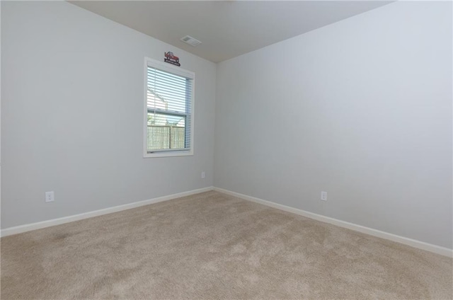 empty room featuring light carpet, visible vents, and baseboards