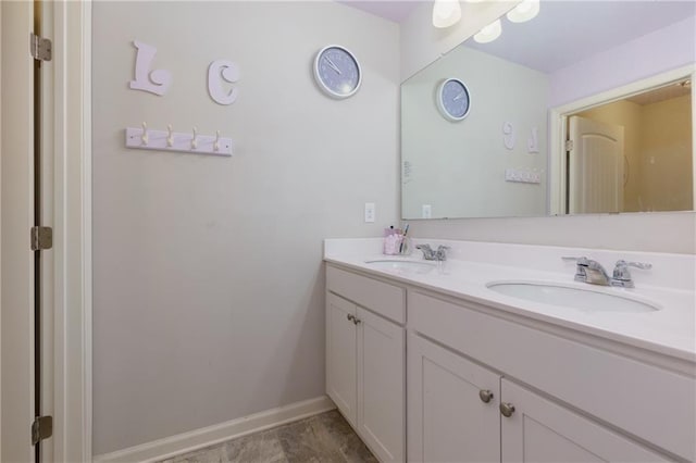 bathroom featuring double vanity, baseboards, and a sink