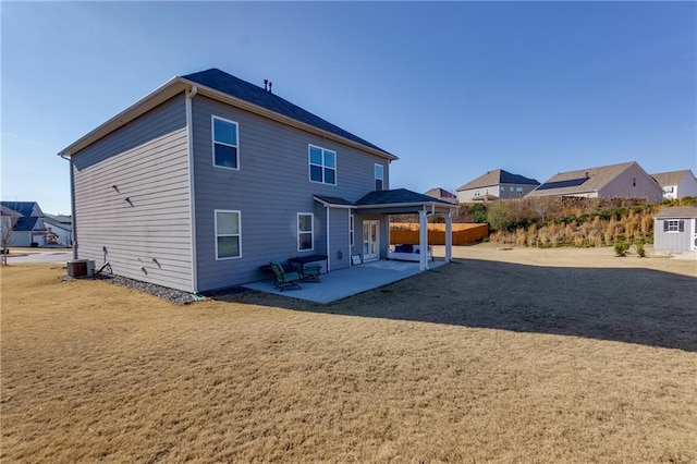 rear view of property featuring a yard, central AC unit, and a patio