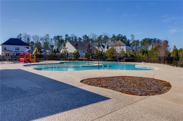 community pool featuring playground community, a residential view, a patio area, and fence