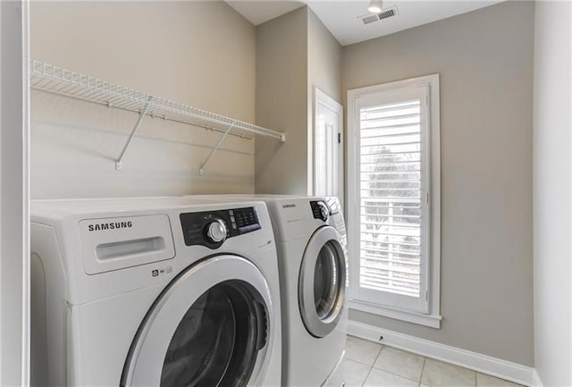 laundry room featuring light tile patterned floors, washer and dryer, and a healthy amount of sunlight