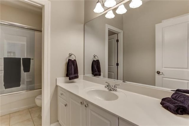 full bathroom with tile patterned flooring, bath / shower combo with glass door, vanity, and toilet