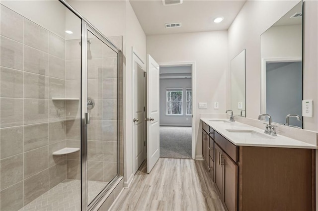 bathroom featuring vanity, wood-type flooring, and a shower with door