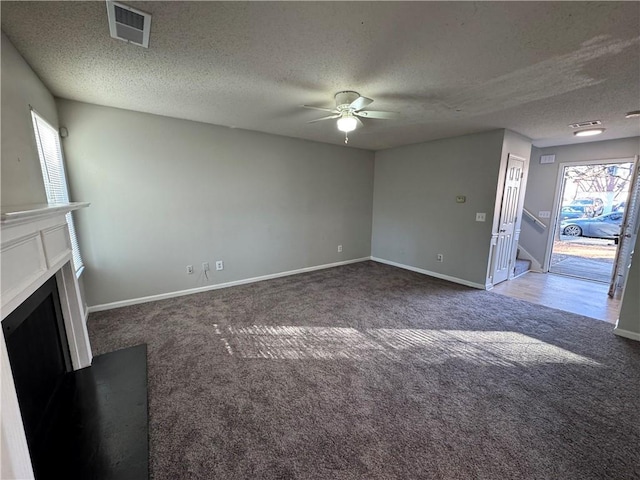 unfurnished living room featuring dark colored carpet, a textured ceiling, and ceiling fan