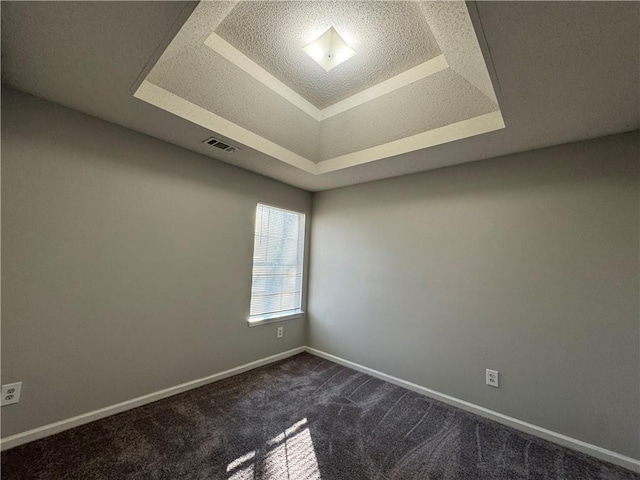 carpeted empty room featuring a textured ceiling and a tray ceiling