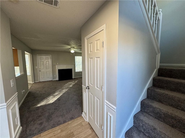 staircase featuring ceiling fan, a healthy amount of sunlight, wood-type flooring, and a textured ceiling