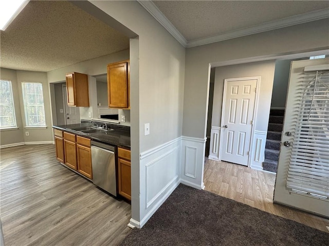 kitchen featuring sink, stainless steel dishwasher, ornamental molding, a textured ceiling, and light hardwood / wood-style floors