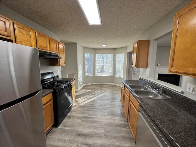 kitchen with sink, stainless steel appliances, a textured ceiling, and light wood-type flooring