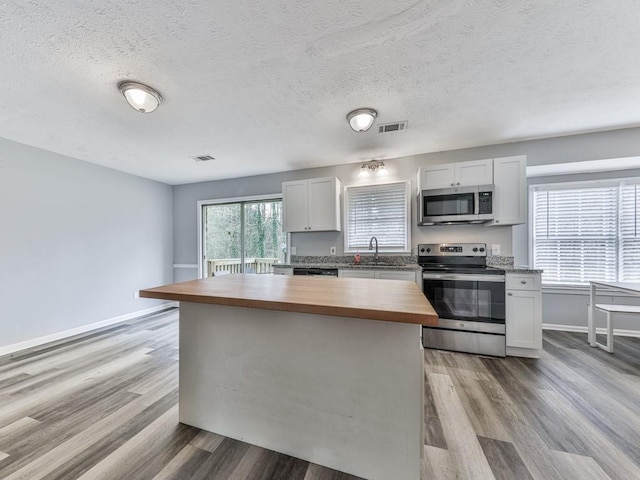 525 Henson Cir, Carrollton, GA 30117 - kitchen featuring butcher block counters, appliances with stainless steel finishes, wood finished floors, a sink, and a textured ceiling
