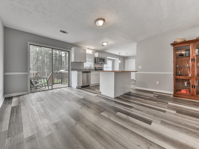 525 Henson Cir, Carrollton, GA 30117 - kitchen featuring stainless steel appliances, light wood finished floors, baseboards, white cabinets, and a textured ceiling