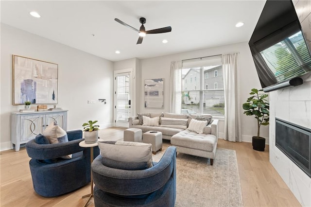 living room featuring a fireplace, light hardwood / wood-style floors, and ceiling fan