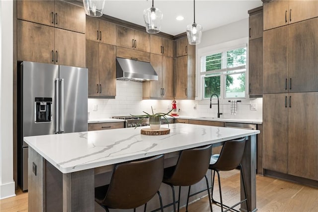 kitchen featuring decorative light fixtures, sink, a center island, exhaust hood, and stainless steel appliances