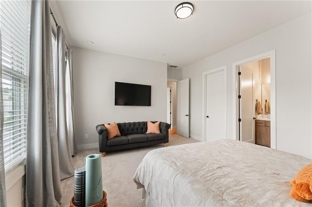 bedroom featuring ensuite bathroom and light carpet