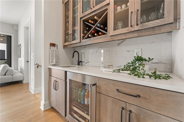 bar featuring wine cooler, light hardwood / wood-style floors, sink, and decorative backsplash