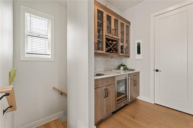 bar with sink, light hardwood / wood-style flooring, wine cooler, and decorative backsplash