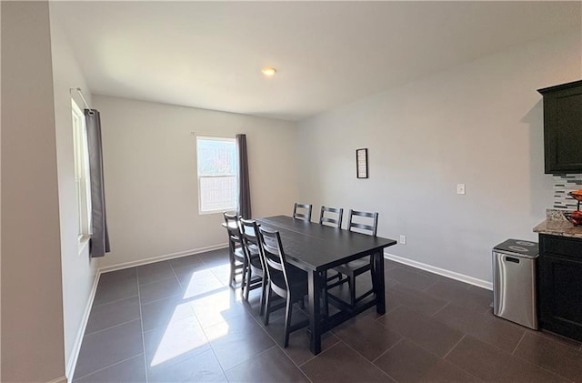 dining room featuring dark tile patterned flooring and baseboards