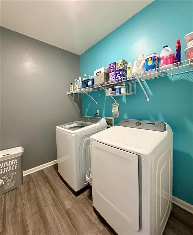 washroom featuring baseboards, laundry area, wood finished floors, and washer and dryer