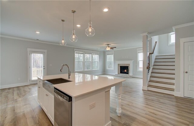 kitchen with pendant lighting, dishwasher, white cabinets, sink, and an island with sink