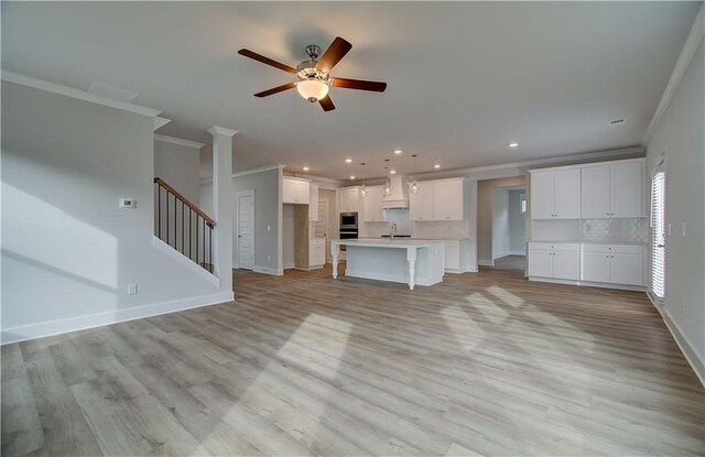 unfurnished living room featuring ceiling fan, sink, crown molding, and light hardwood / wood-style flooring