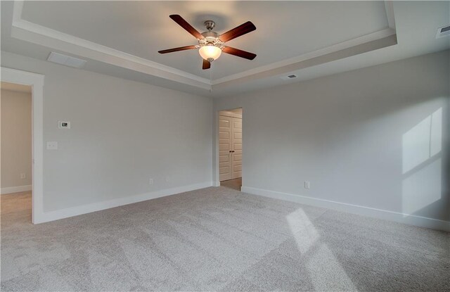 carpeted spare room featuring ceiling fan, ornamental molding, and a tray ceiling