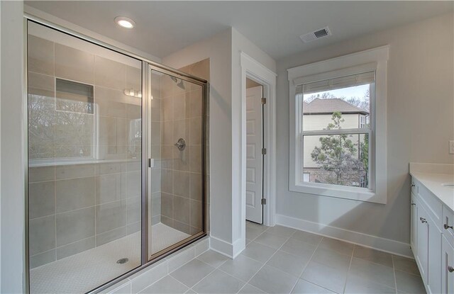 bathroom with a shower with door, vanity, and tile patterned flooring