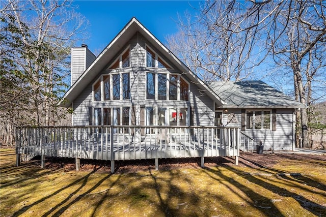 back of property with a lawn, a deck, and a chimney