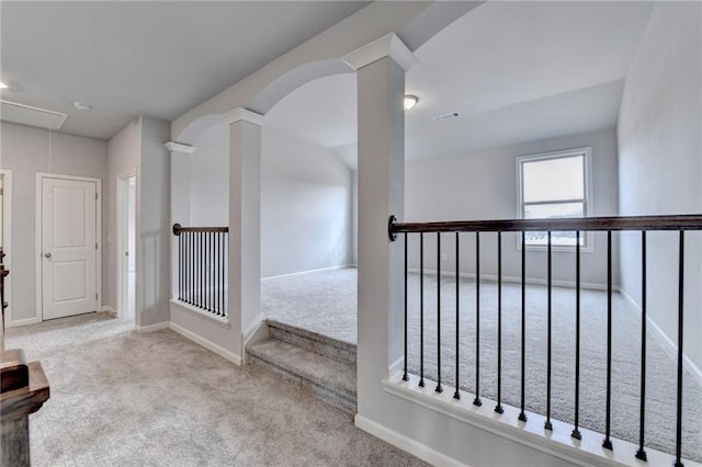 hall with decorative columns and light colored carpet