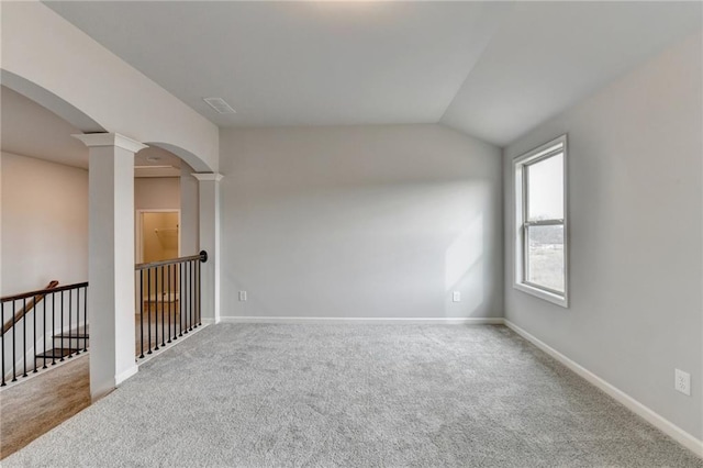 unfurnished room featuring carpet floors, vaulted ceiling, and ornate columns